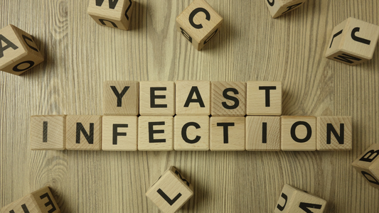 Wooden letter blocks spelling out "YEAST INFECTION" on a wooden surface