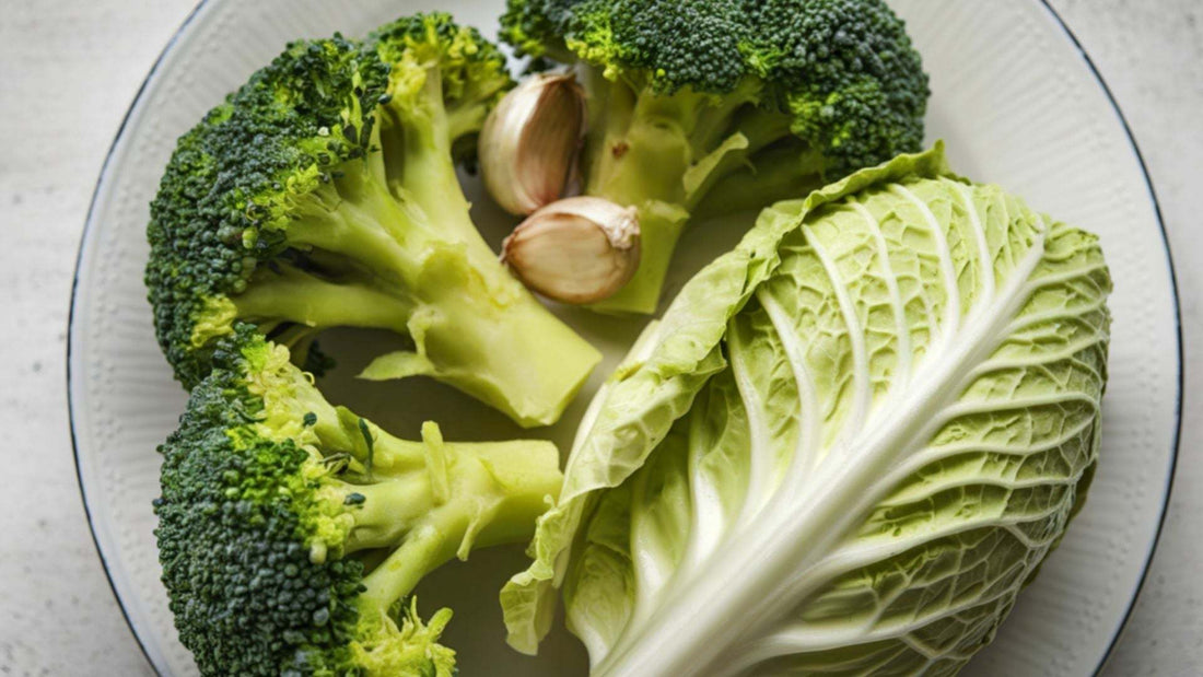 Broccoli florets, cabbage leaf, and garlic cloves on a clear glass plate for cancer prevention diet