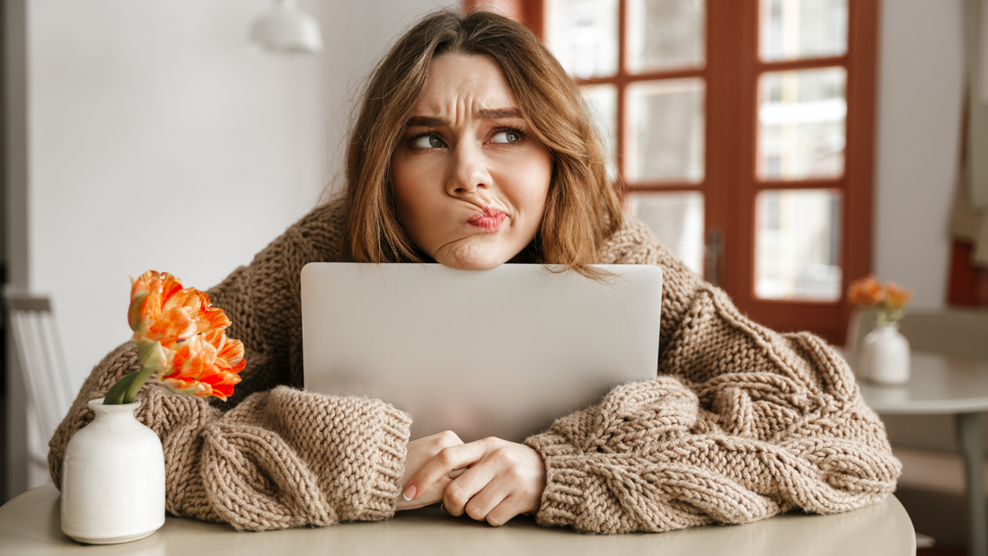 Confused woman holding laptop with worried expression indoors, symbolizing yeast infections concerns and tips.