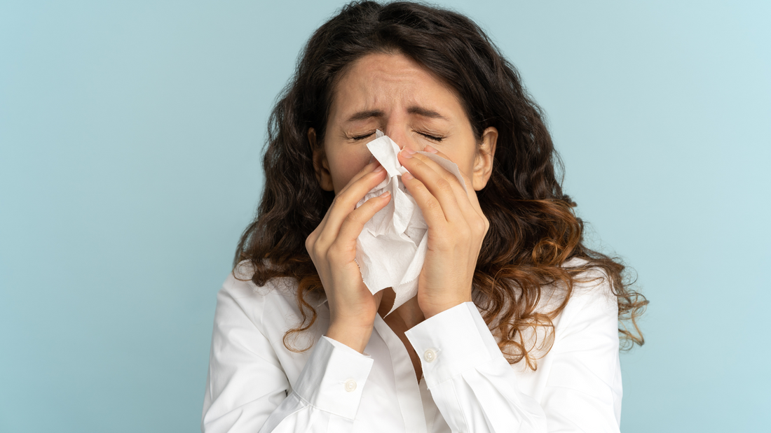 woman blowing nose into tissue with bird flu symptoms on blue background