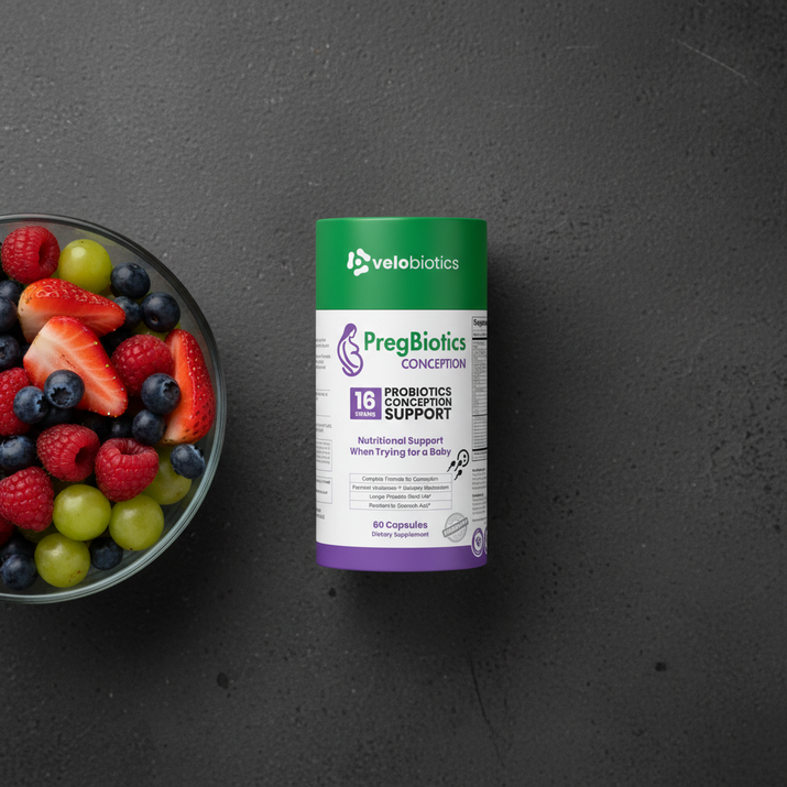 PregBiotics Conception probiotic supplement for conception support with preconception vitamins and minerals displayed beside a bowl of fresh mixed berries and grapes on dark surface