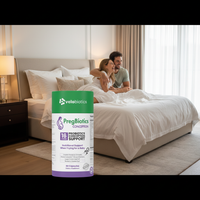 PregBiotics Conception supplement bottle in bedroom setting with couple embracing on bed, supports gut health and preconception wellness.